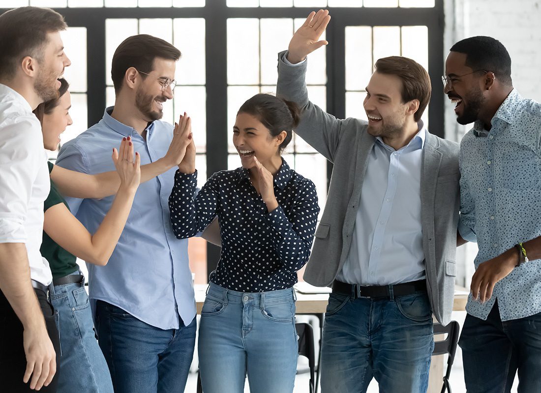 Insurance Solutions - Happy Group of Business Professionals Cheering and Giving Hive Fives at an Office